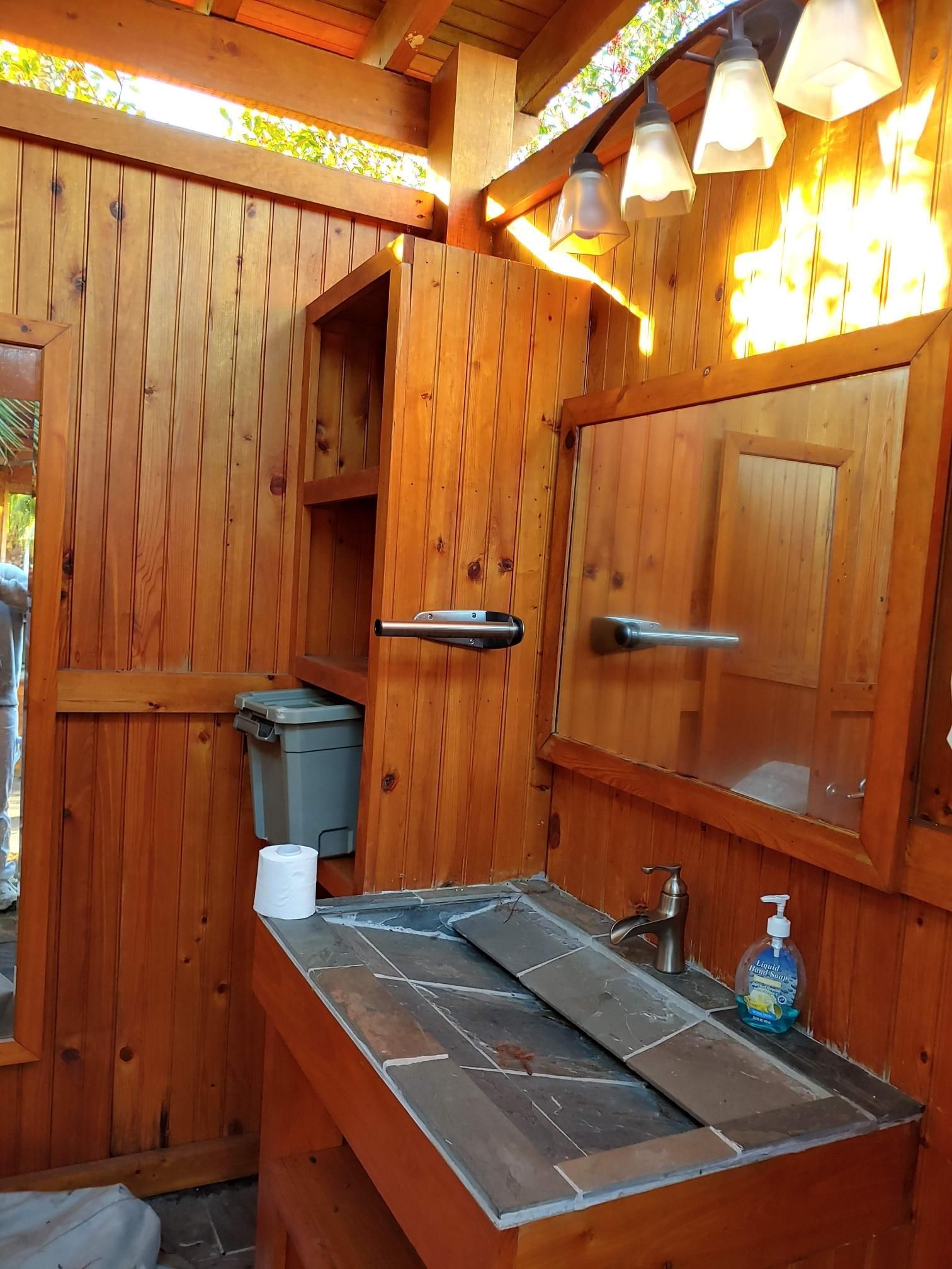 A bathroom with wooden walls and a sink and mirror