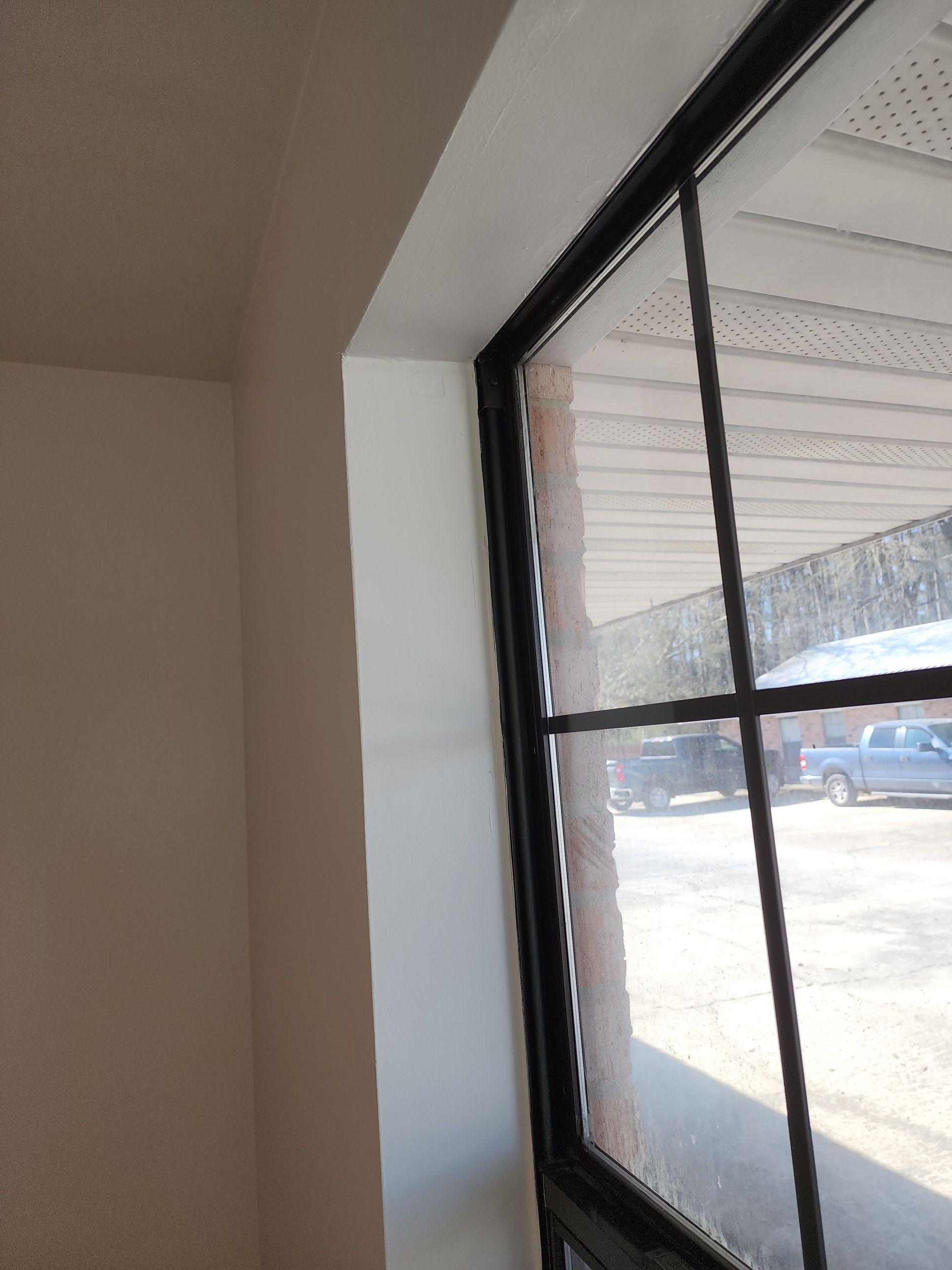 A window with a black frame is in a room with a white wall.