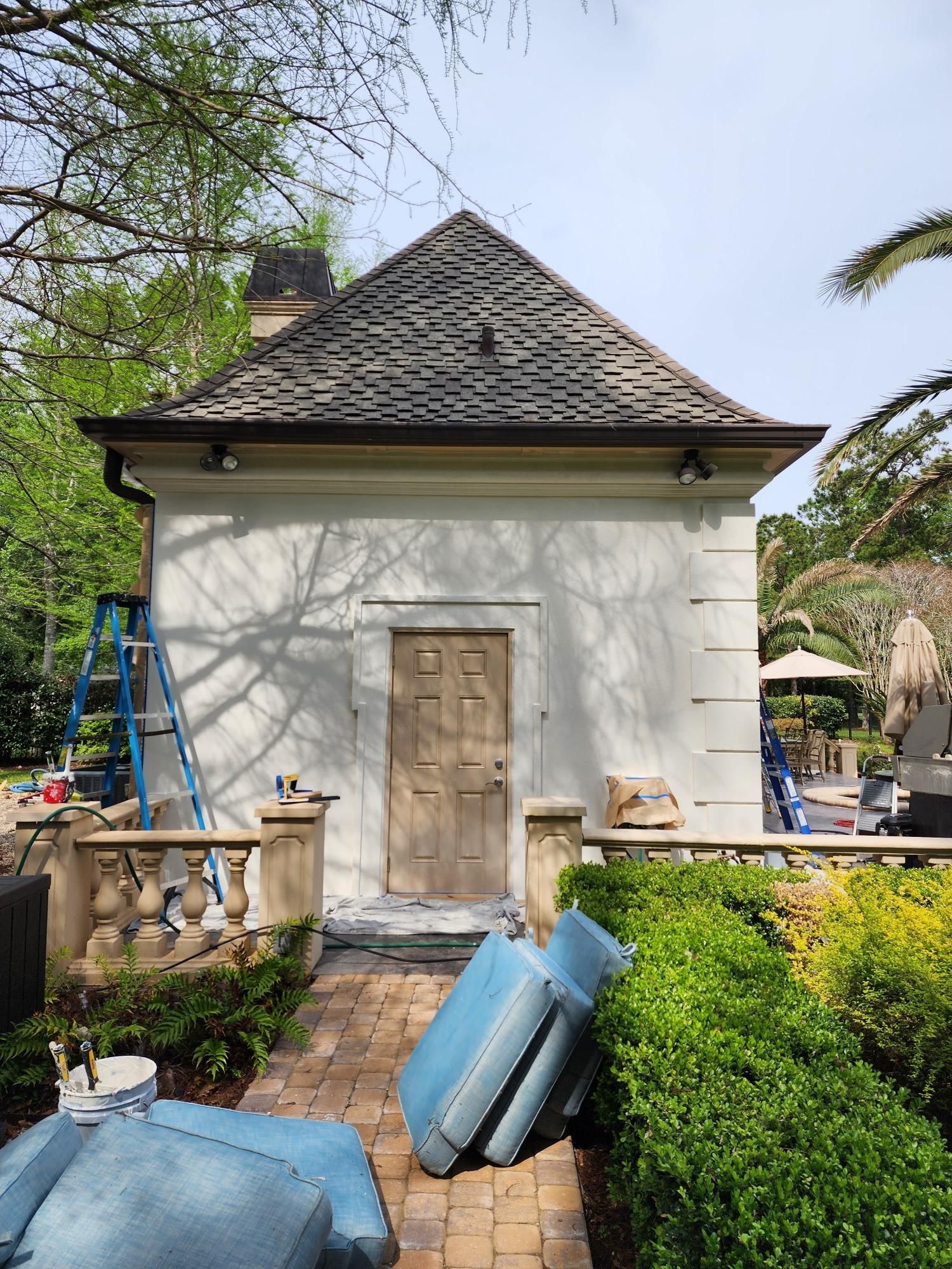 A white house with a ladder in front of it is being painted.