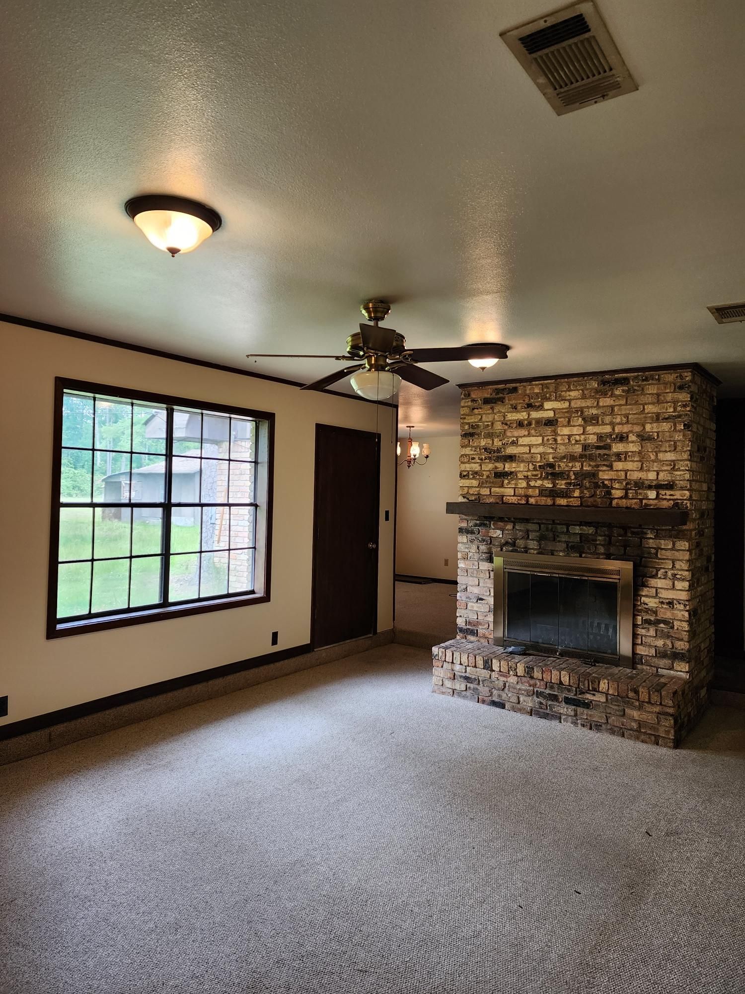 An empty living room with a fireplace and a ceiling fan