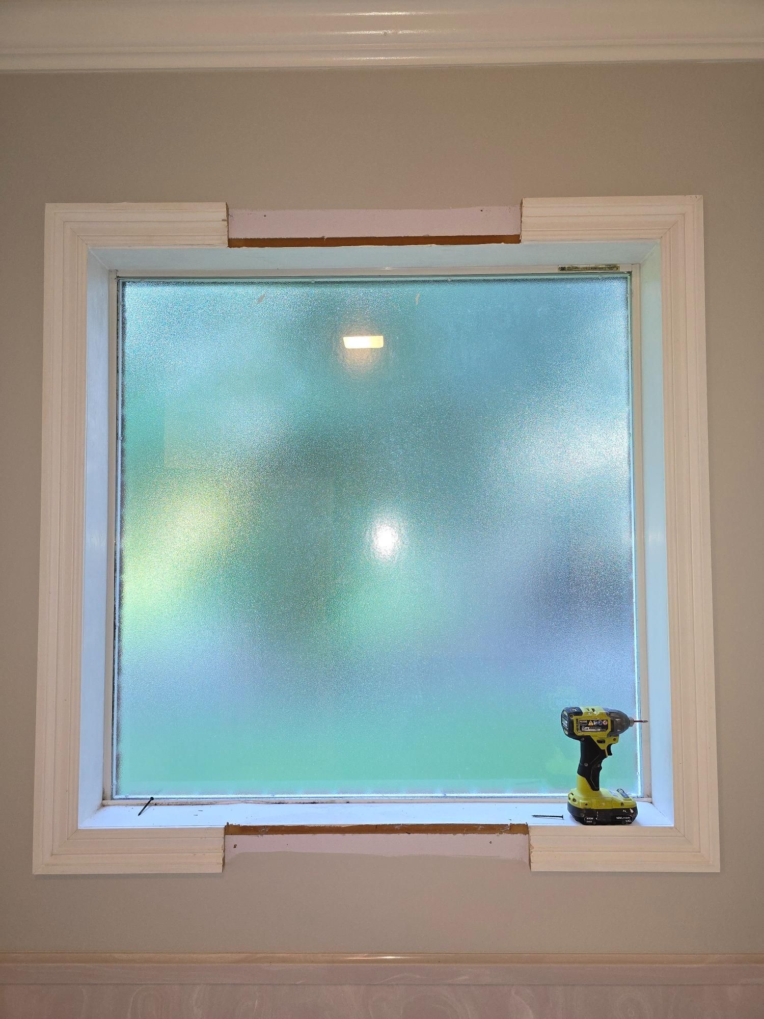 A window with a drill in the corner of it.