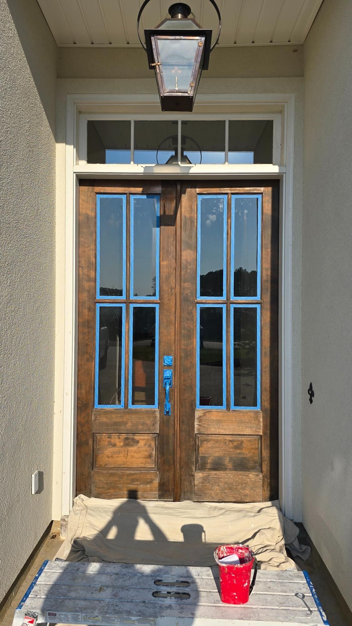 A wooden door with blue trim is being painted.