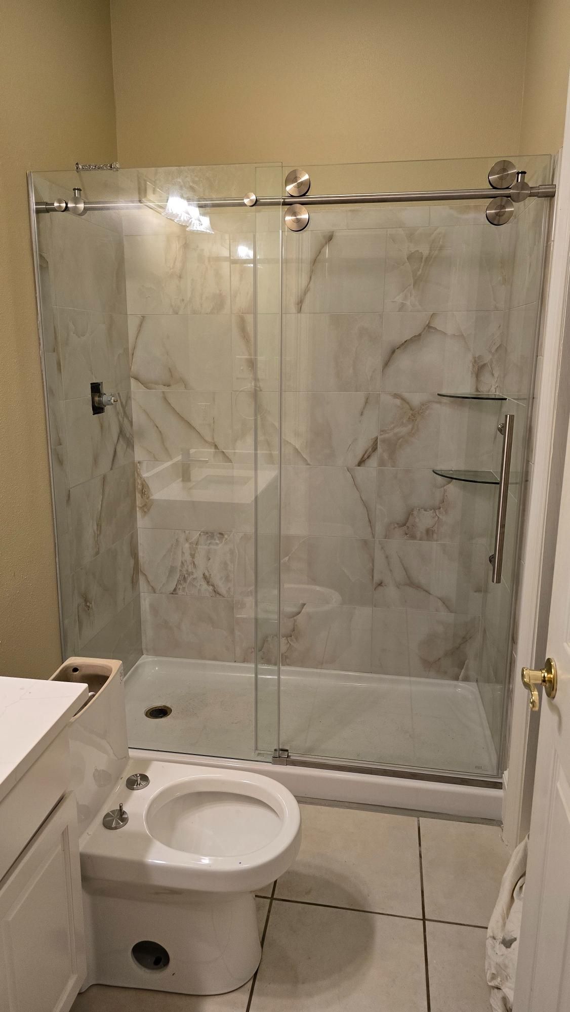 A bathroom with a toilet , sink , shower and sliding glass door.
