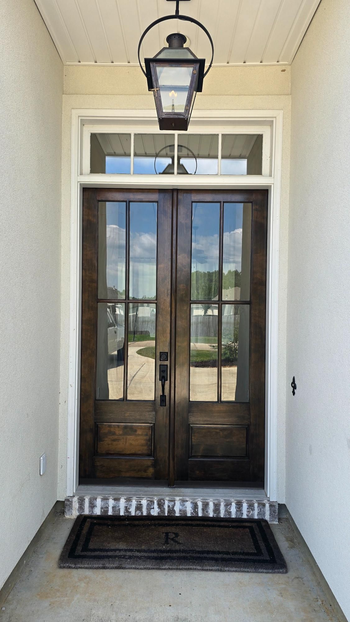 The front door of a house has a lantern hanging from the ceiling above it.