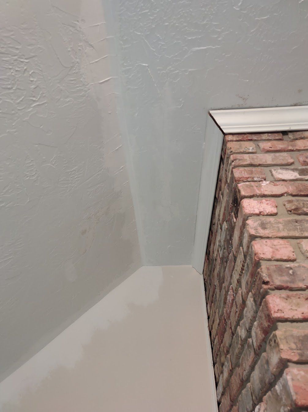 There is a brick fireplace in the corner of the room.