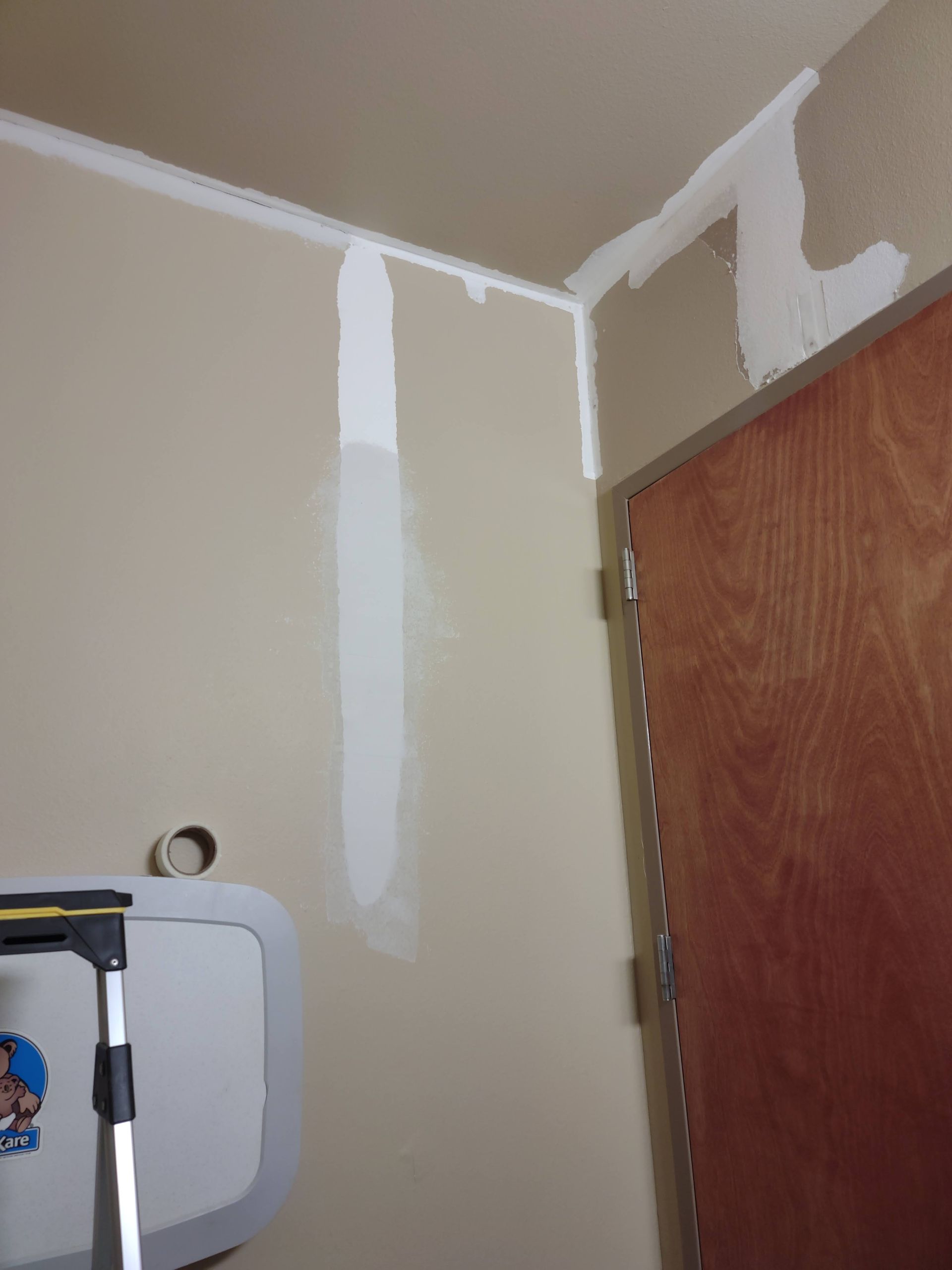 A bathroom with a toilet and a door that is being painted.