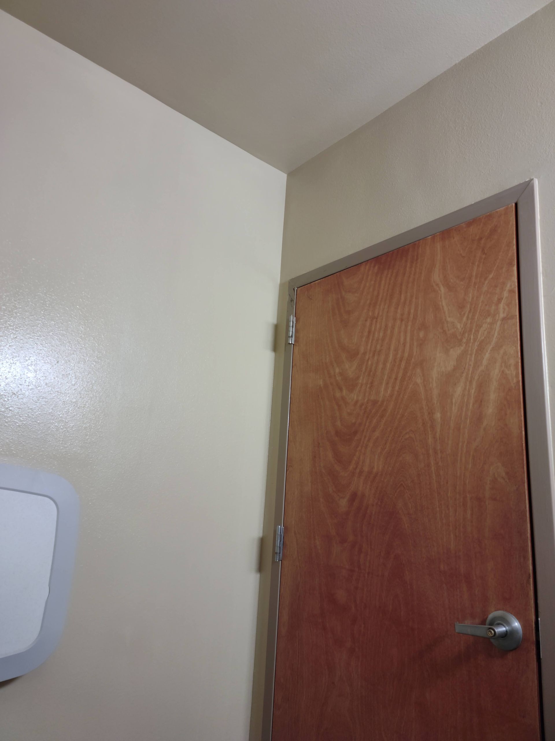 A bathroom with a wooden door and a paper towel dispenser