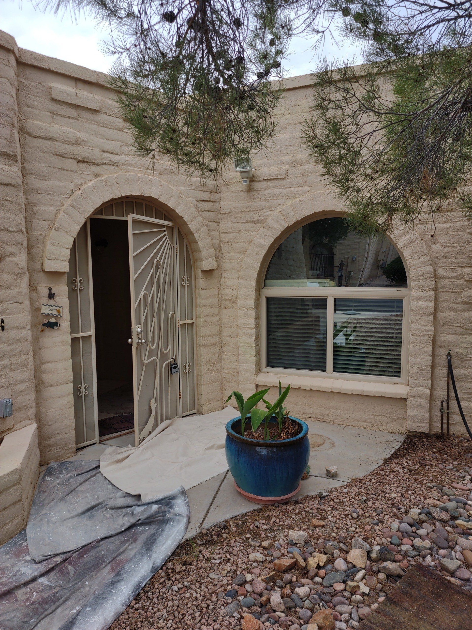 A brick building with arched windows and a blue potted plant in front of it.