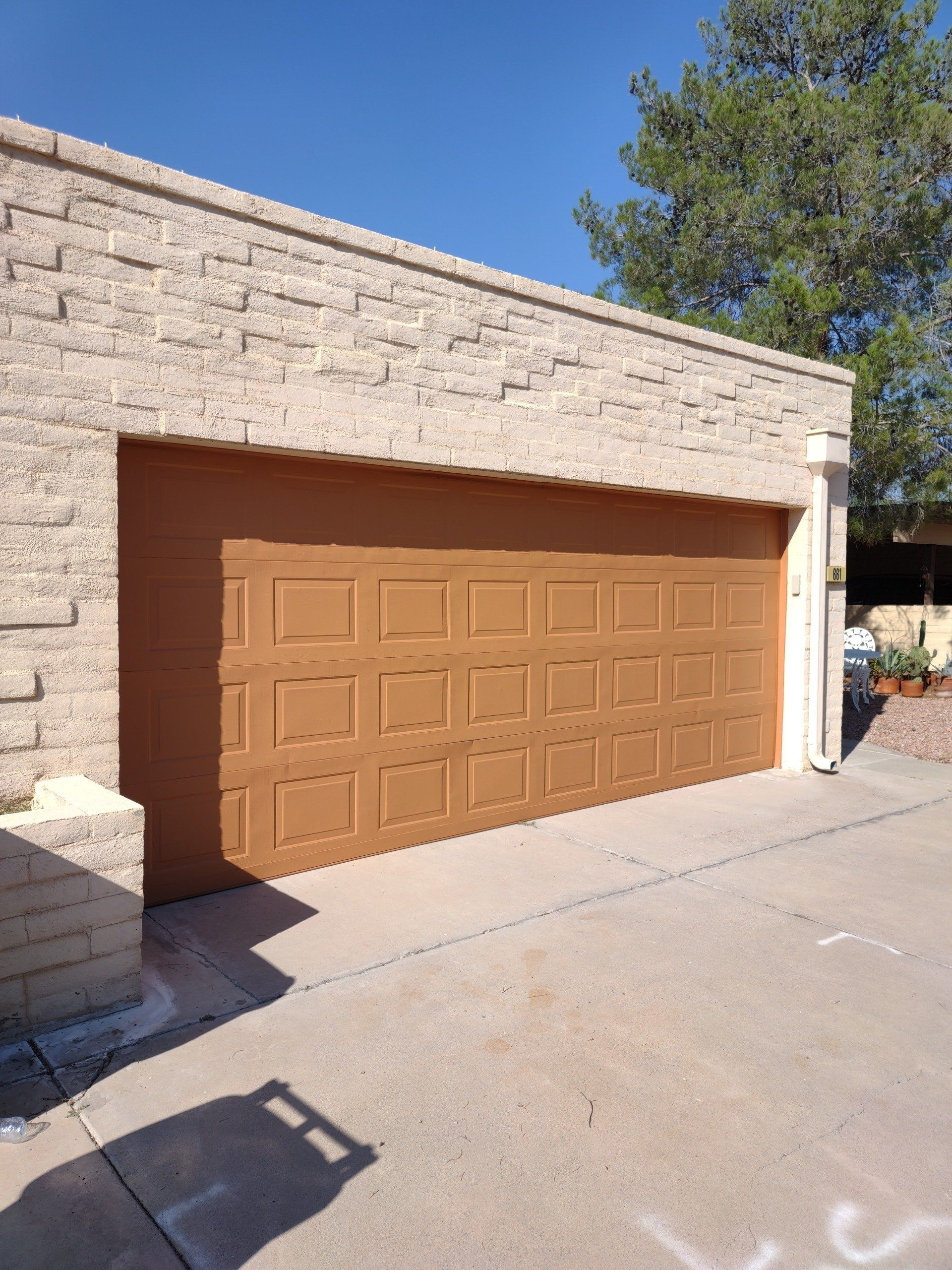 A brown garage door is on a brick building