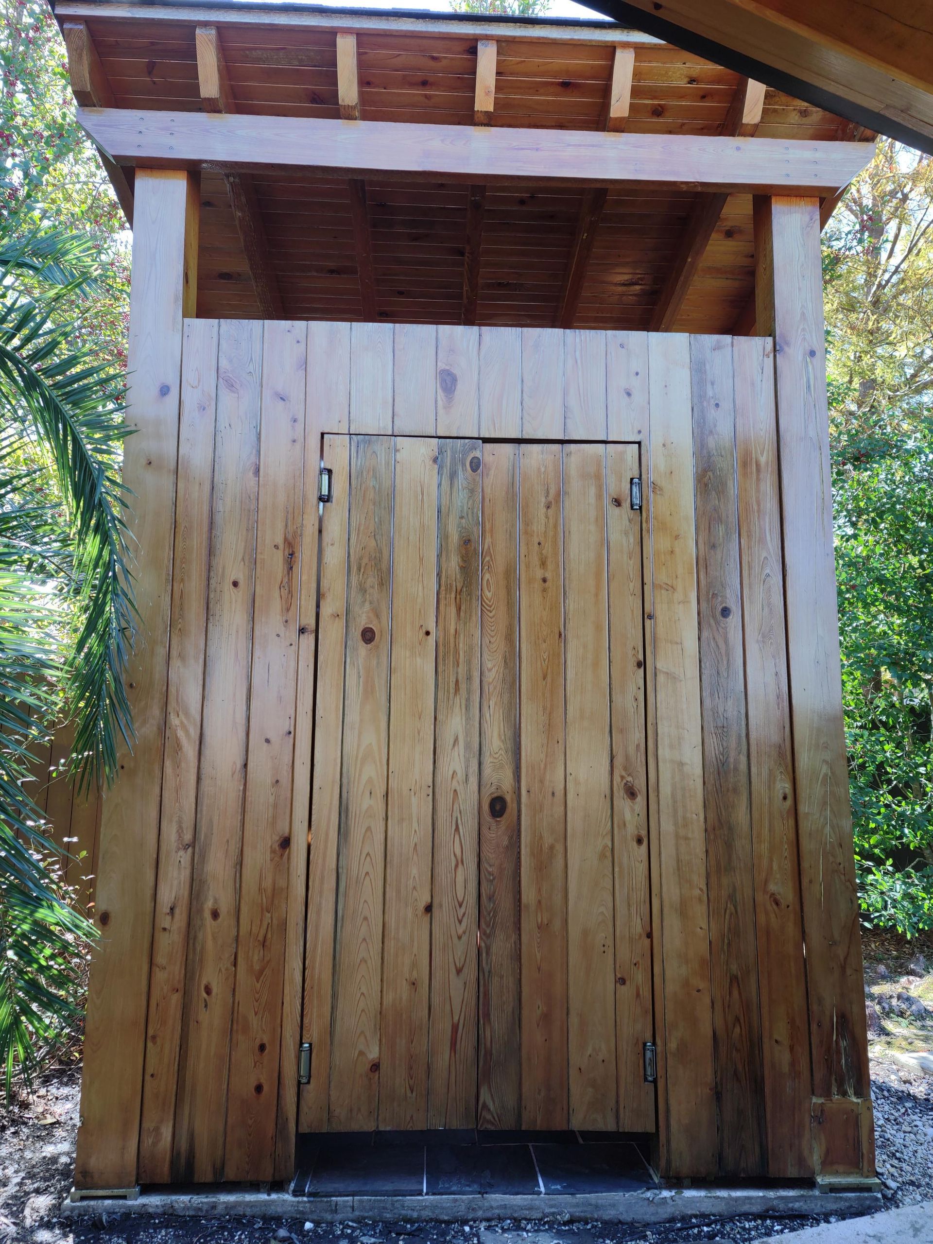 A wooden shed with a door and a roof