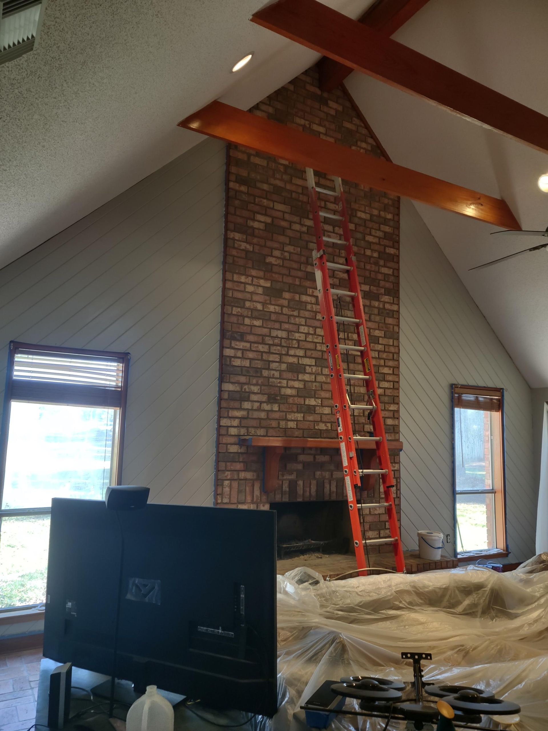 A living room with a brick fireplace and a ladder