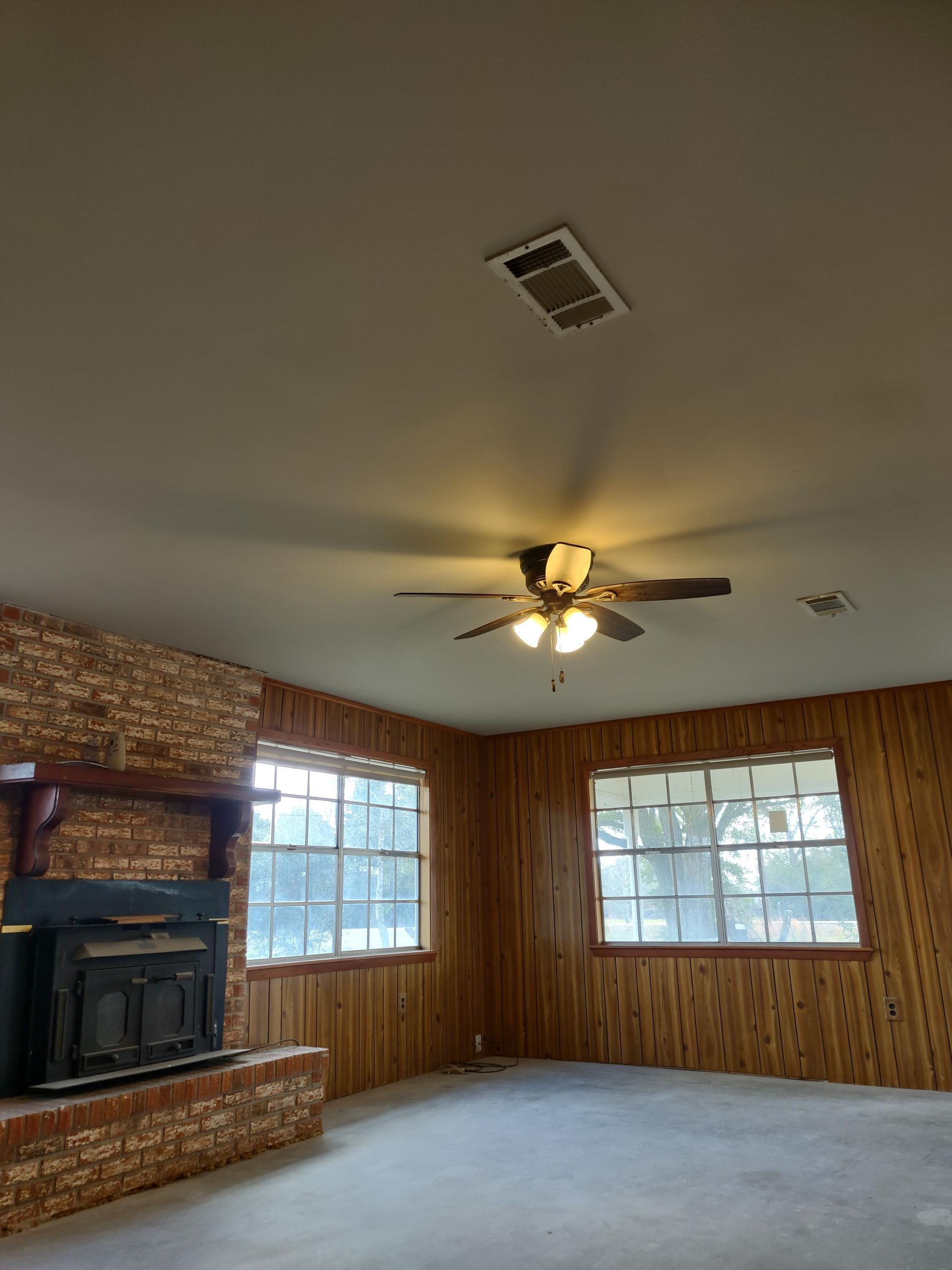 A living room with a fireplace and a ceiling fan
