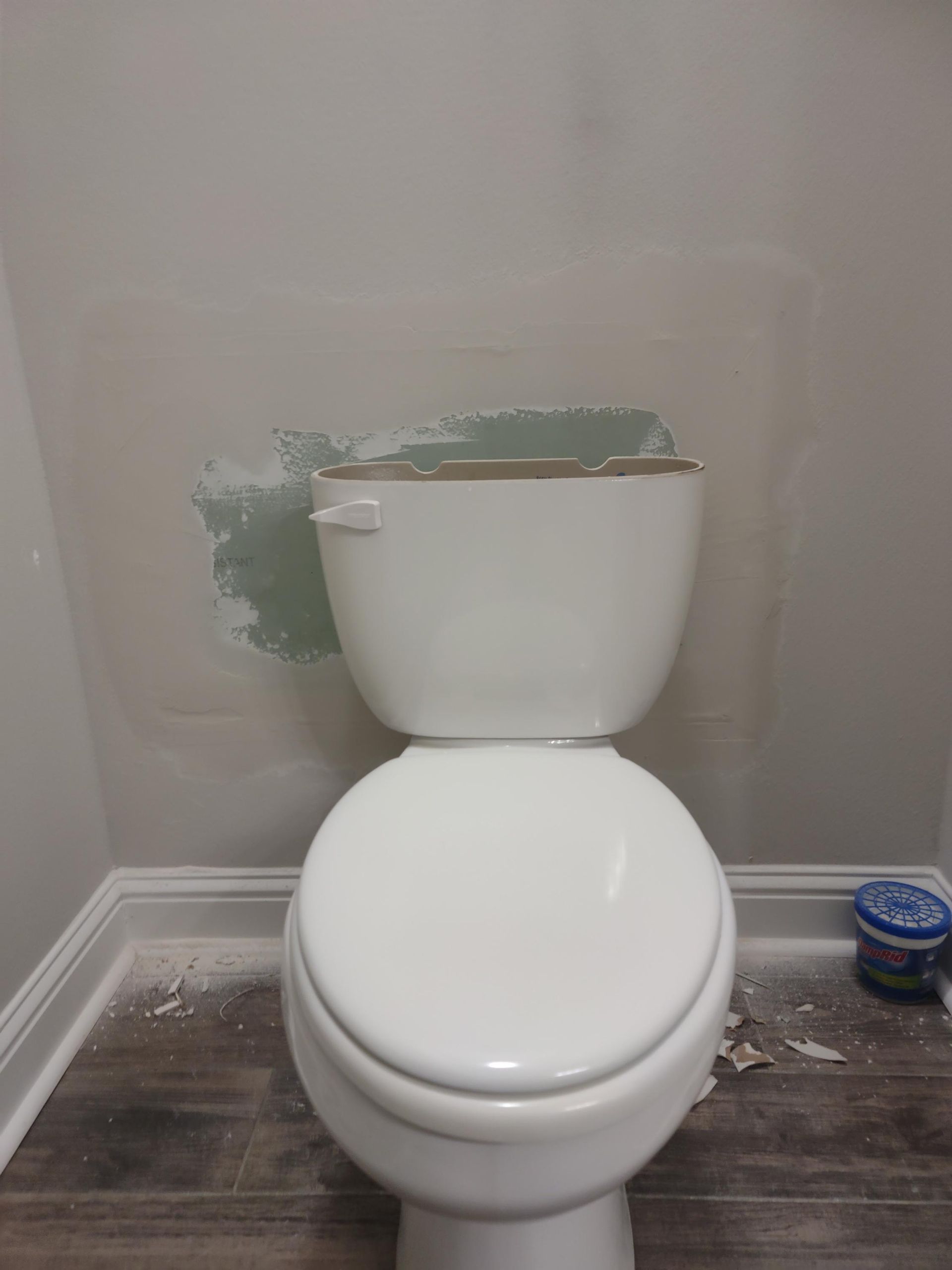A white toilet is sitting in a bathroom next to a wall.