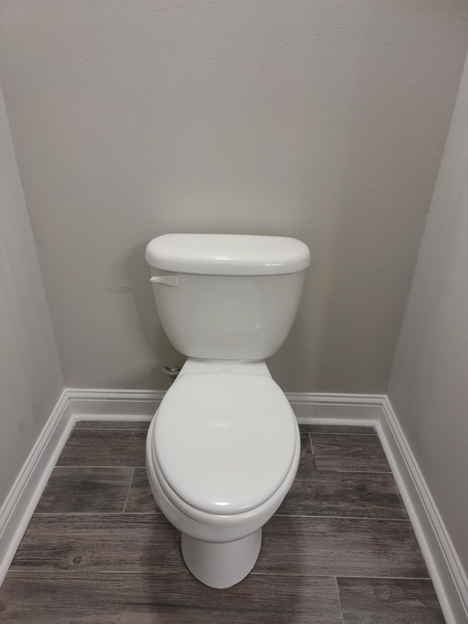 A white toilet is sitting in a corner of a bathroom.