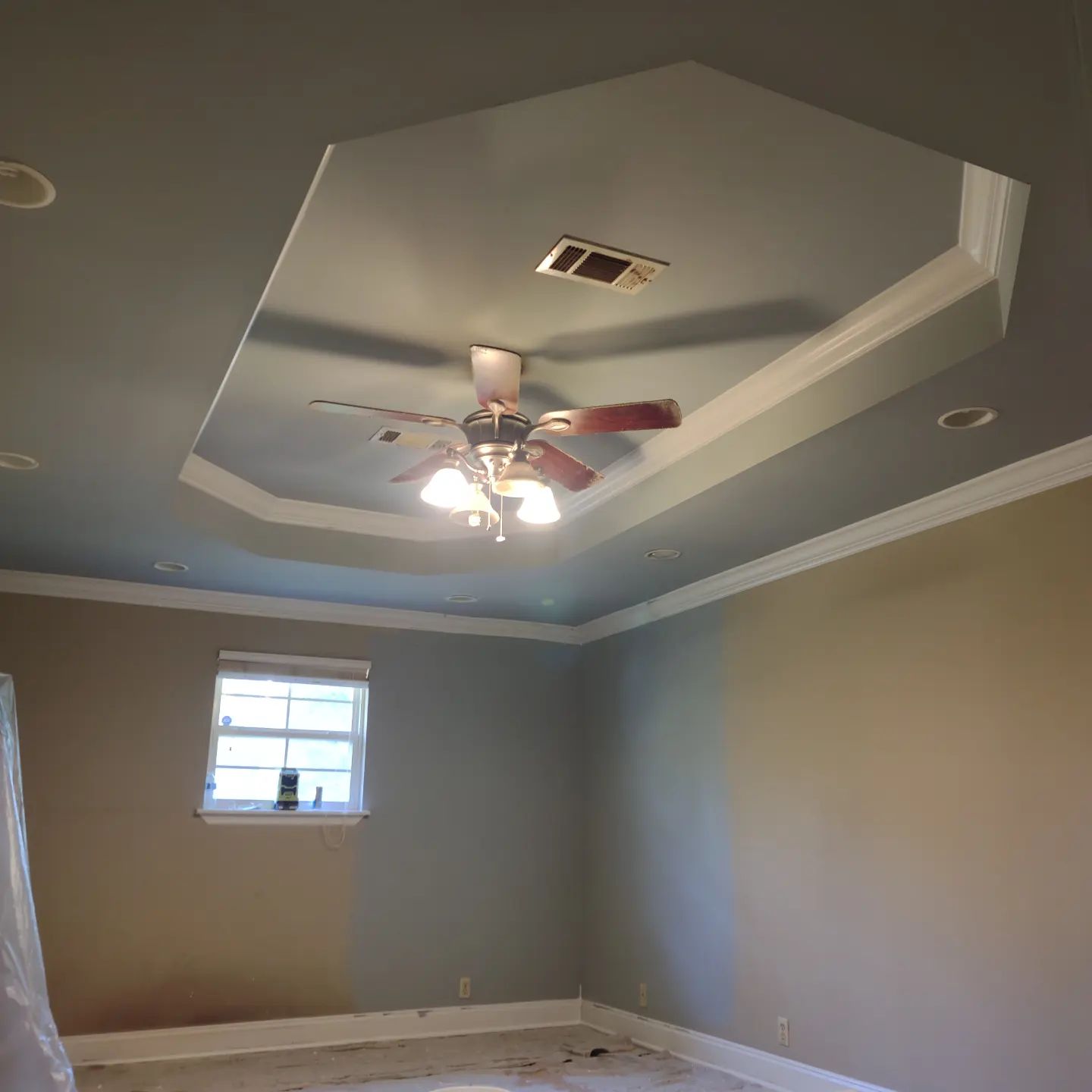 A bedroom with a ceiling fan and a window.