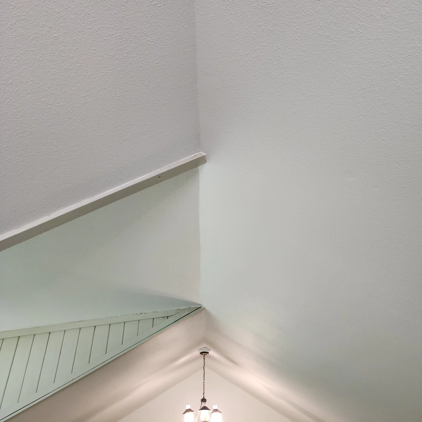 A staircase with a glass railing and a chandelier hanging from the ceiling