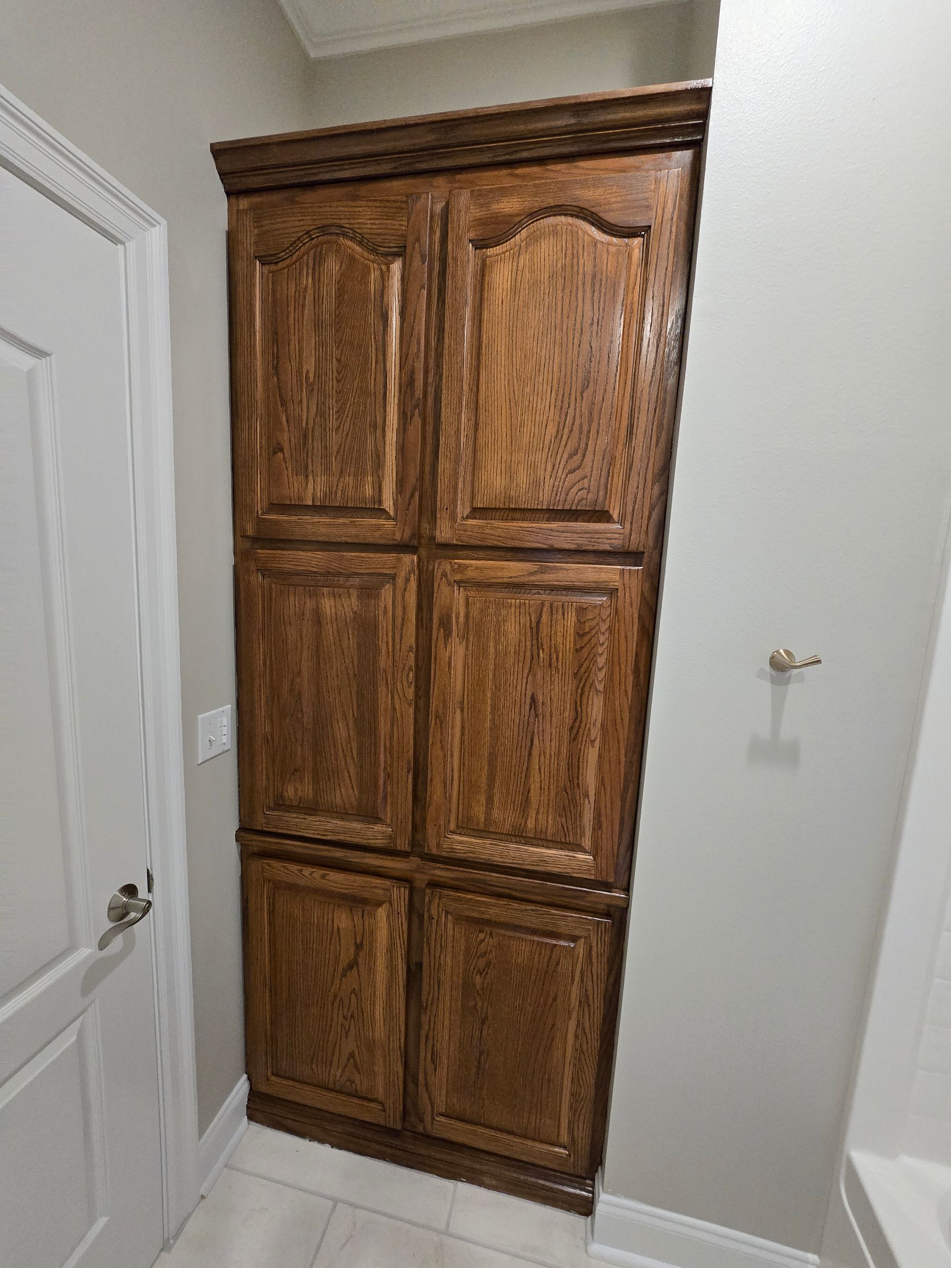A large wooden cabinet in a bathroom next to a door.