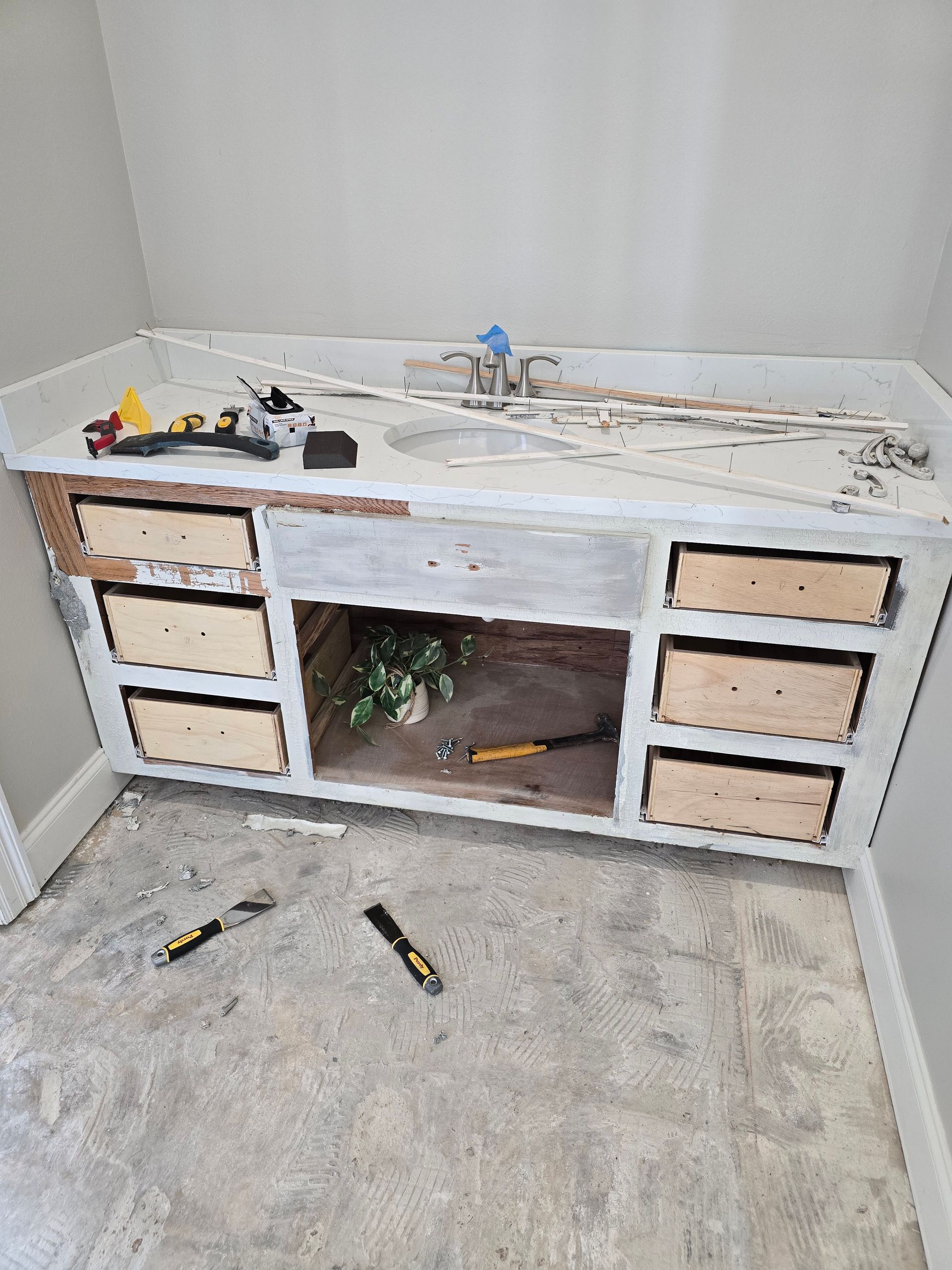 A bathroom vanity is being remodeled with a sink and drawers.