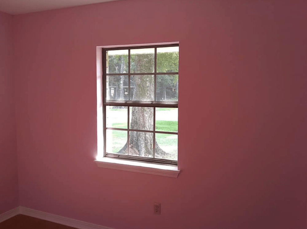 A room with pink walls and a window with a tree outside