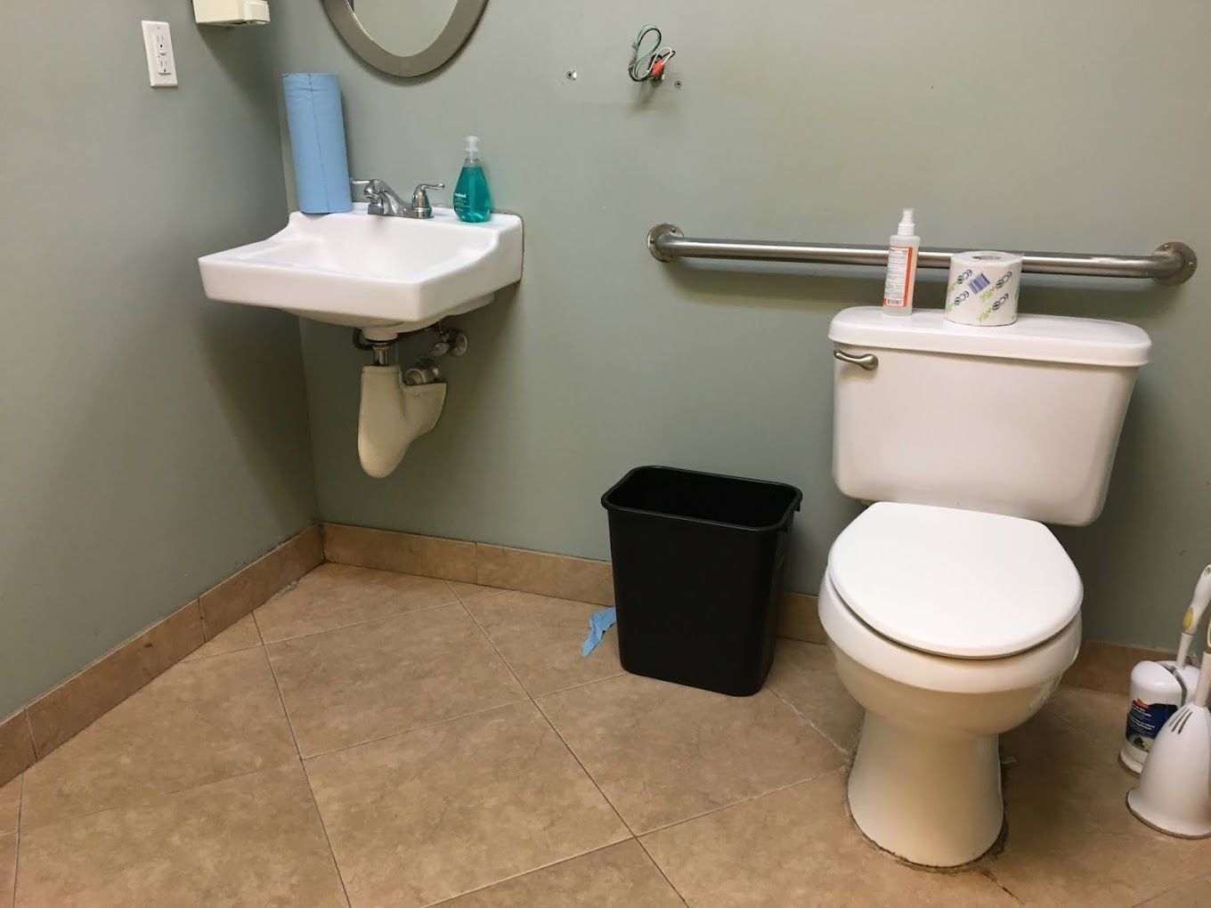 A bathroom with a toilet , sink and trash can