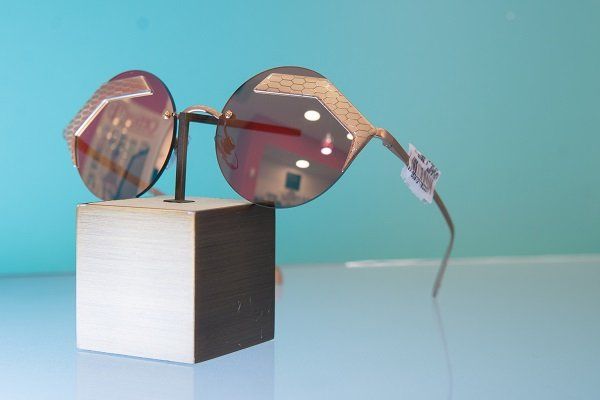 Occhiali da sole esposti su un blocco di legno con sfondo azzurro.