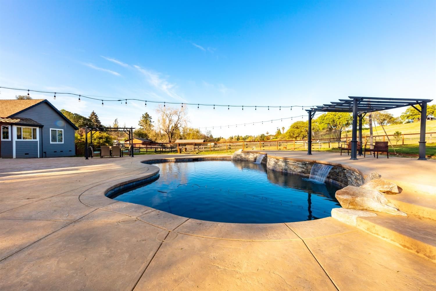 There is a large swimming pool in the backyard of a house.