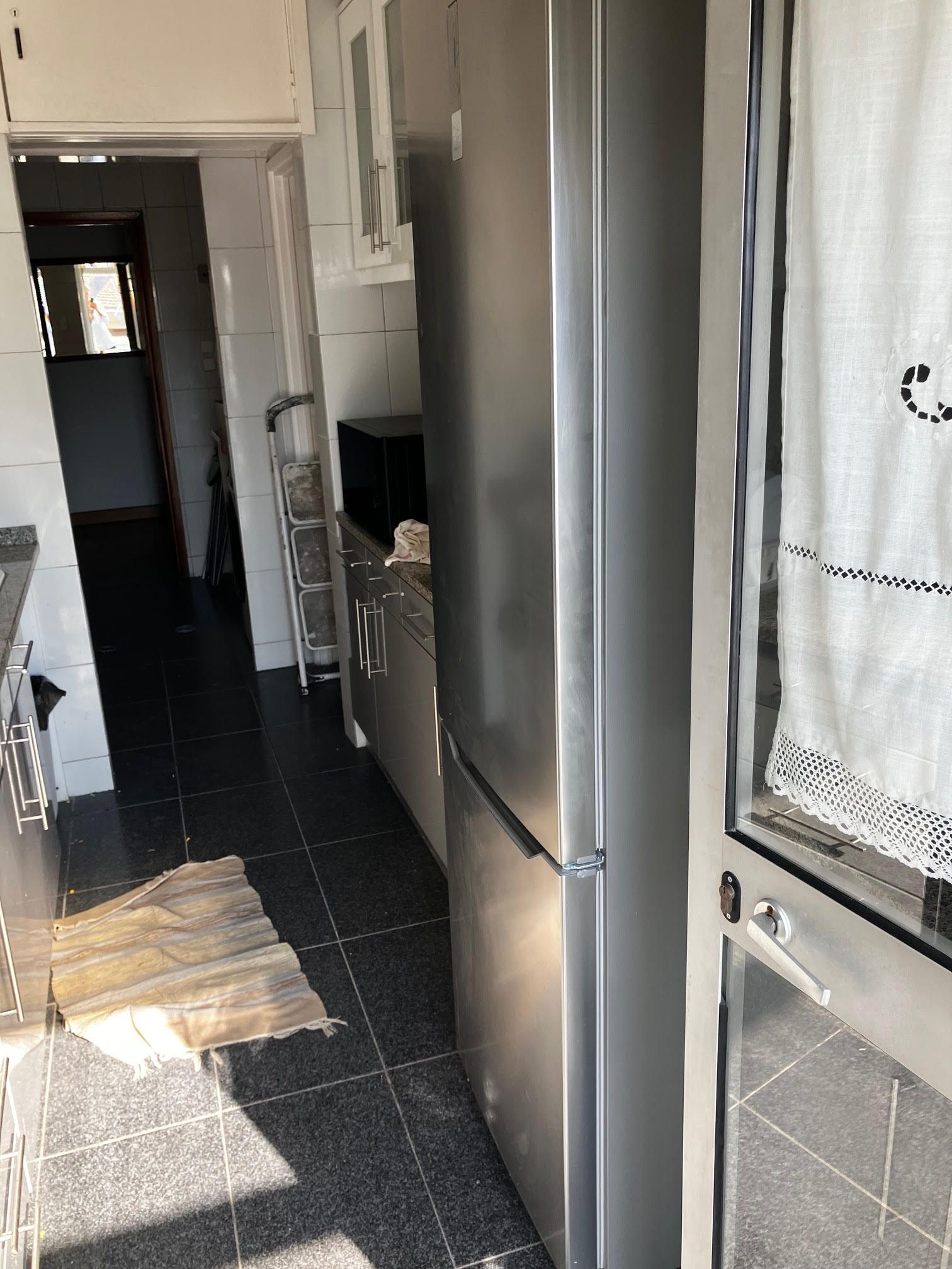 A stainless steel refrigerator is in a kitchen next to a window