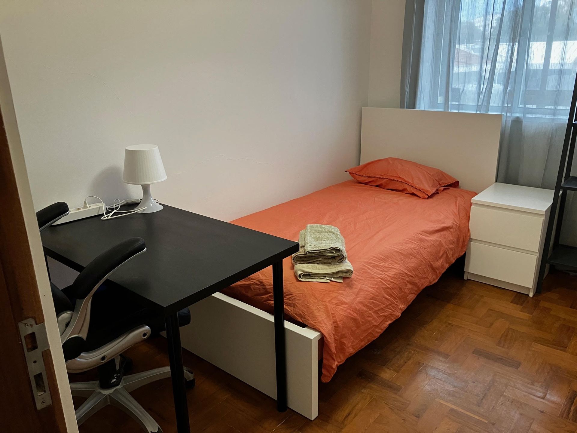 A bedroom with a single bed and a desk