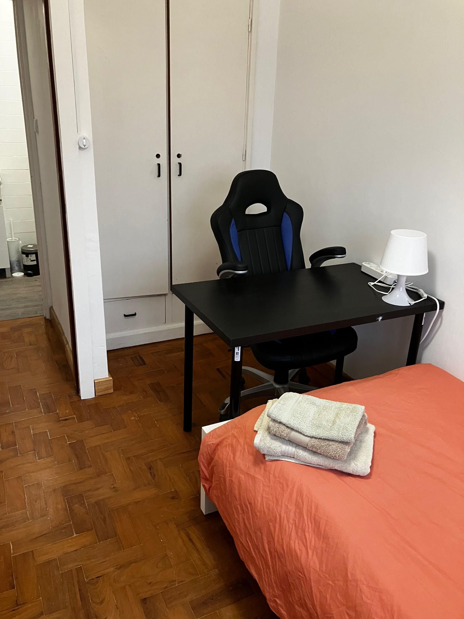 A bedroom with a bed a desk and a chair