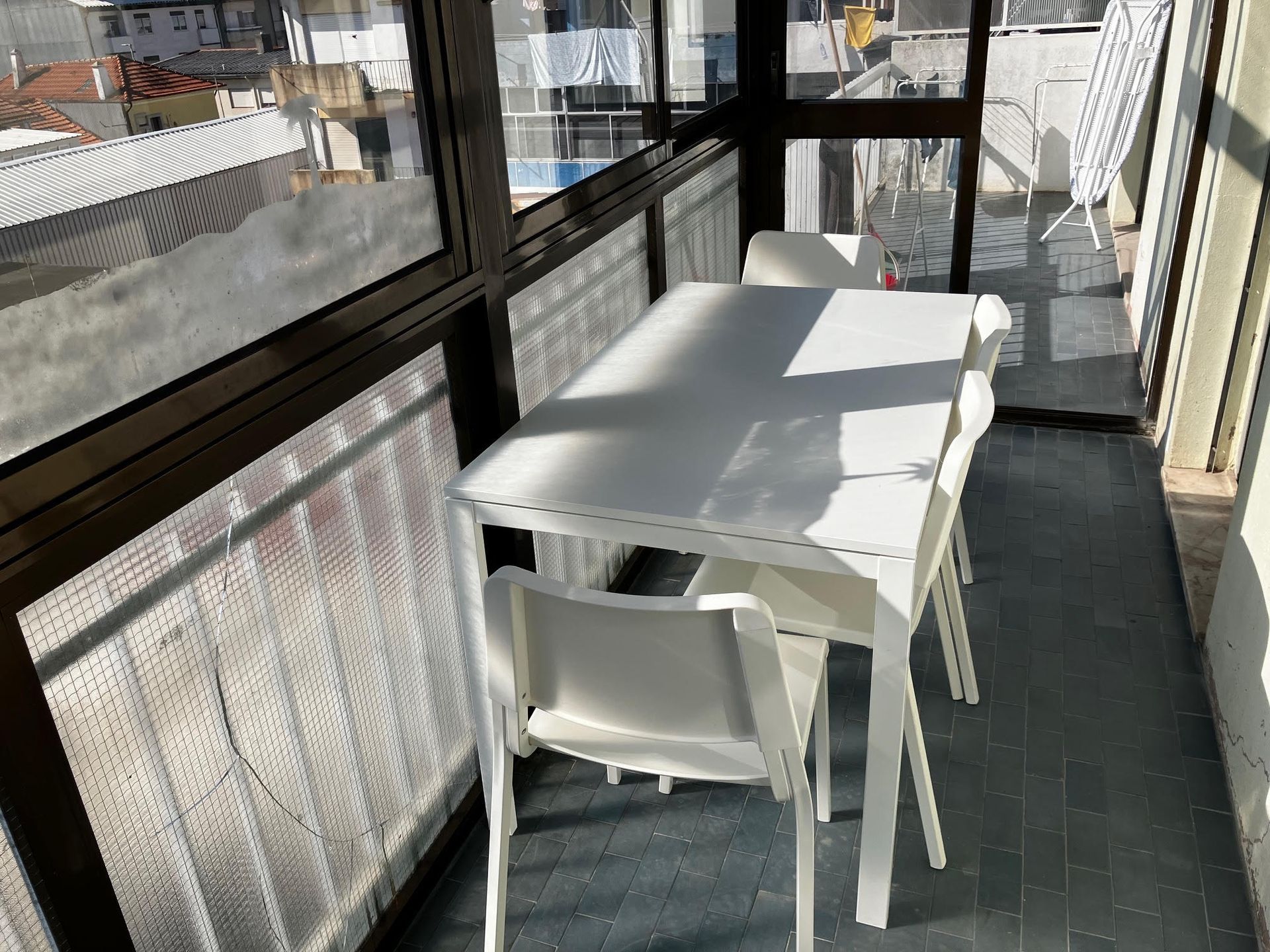 A balcony with a white table and chairs