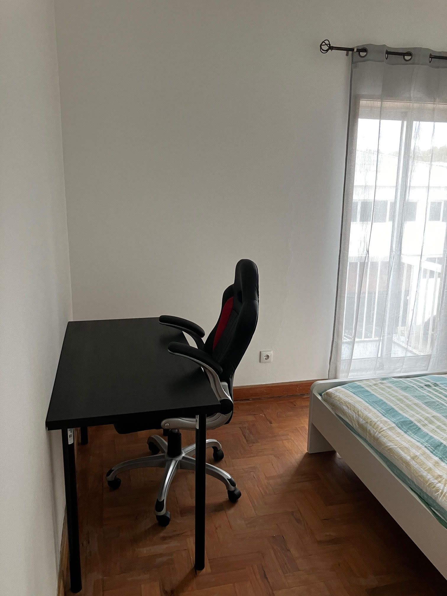 A bedroom with a desk and chair in front of a window