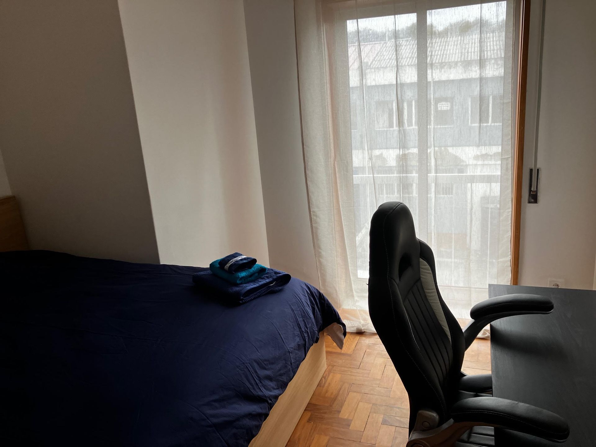 A bedroom with a bed a desk and a chair