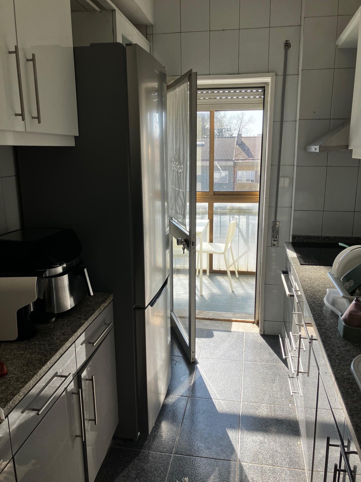 A kitchen with a sliding glass door that leads to a balcony