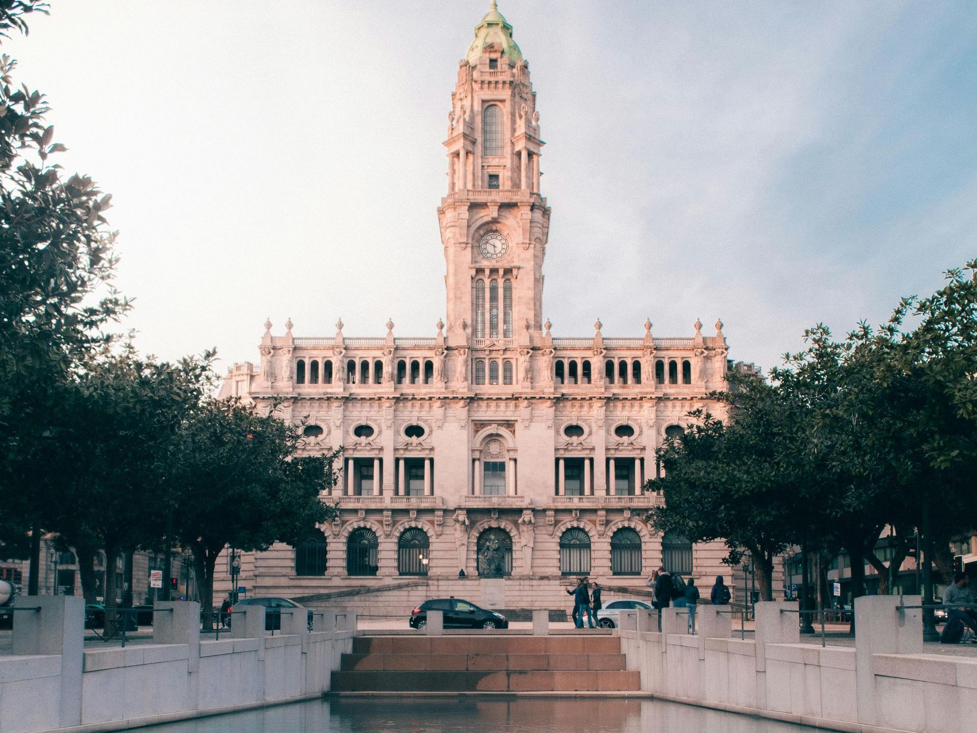 A large building with a clock tower and a fountain in front of it