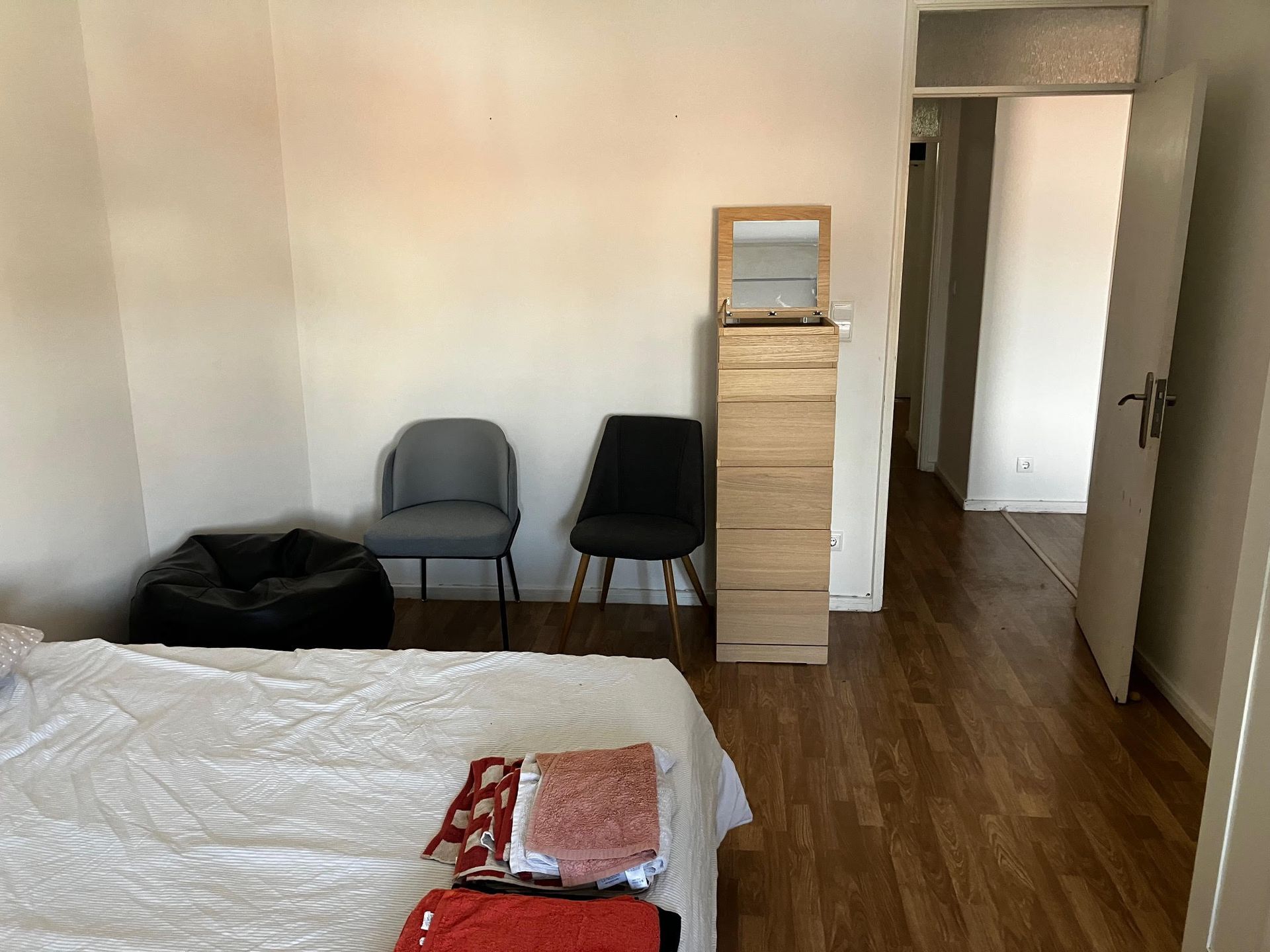 A bedroom with a bed and chairs and a mirror