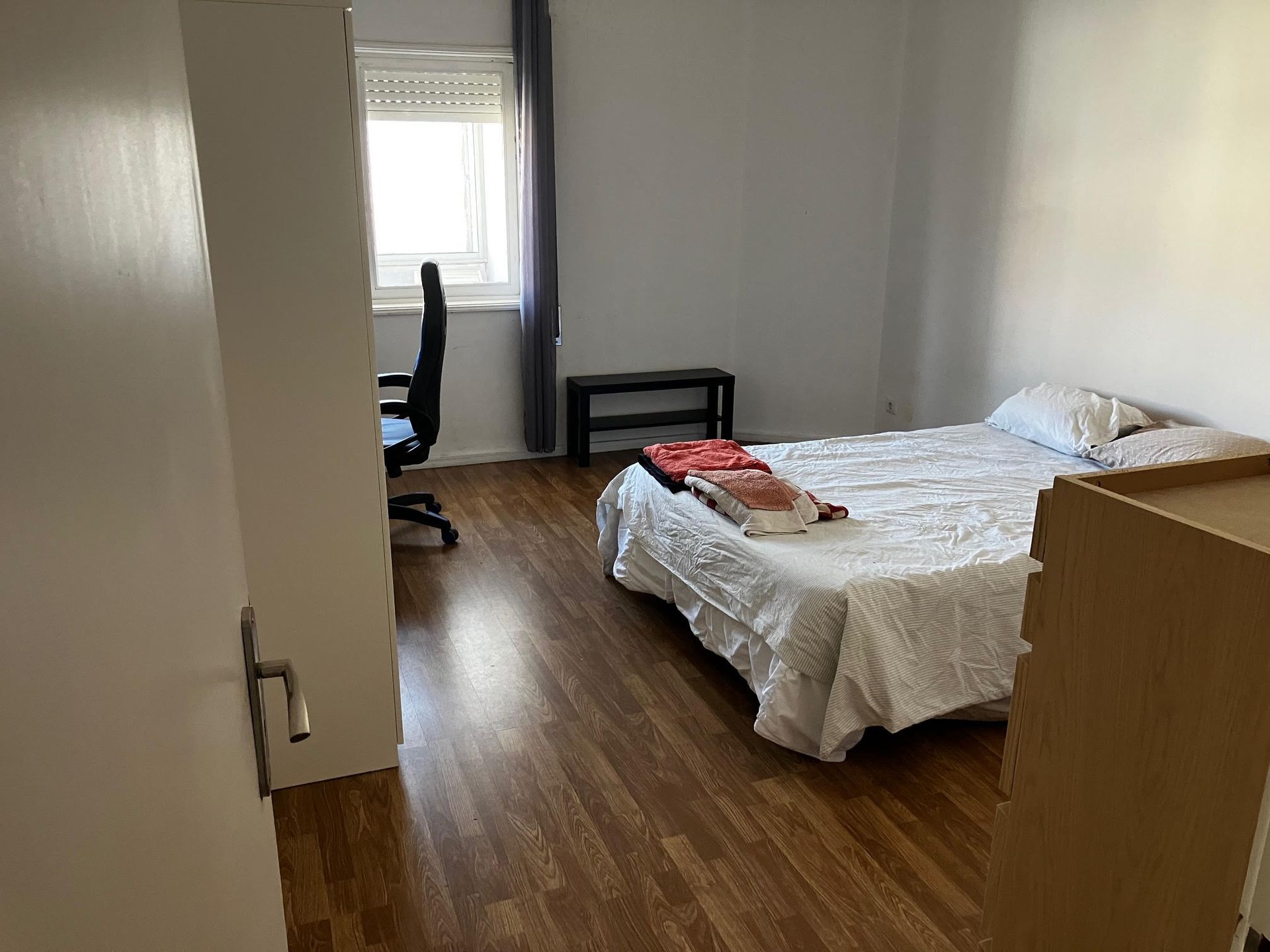 A bedroom with a bed a desk and a window