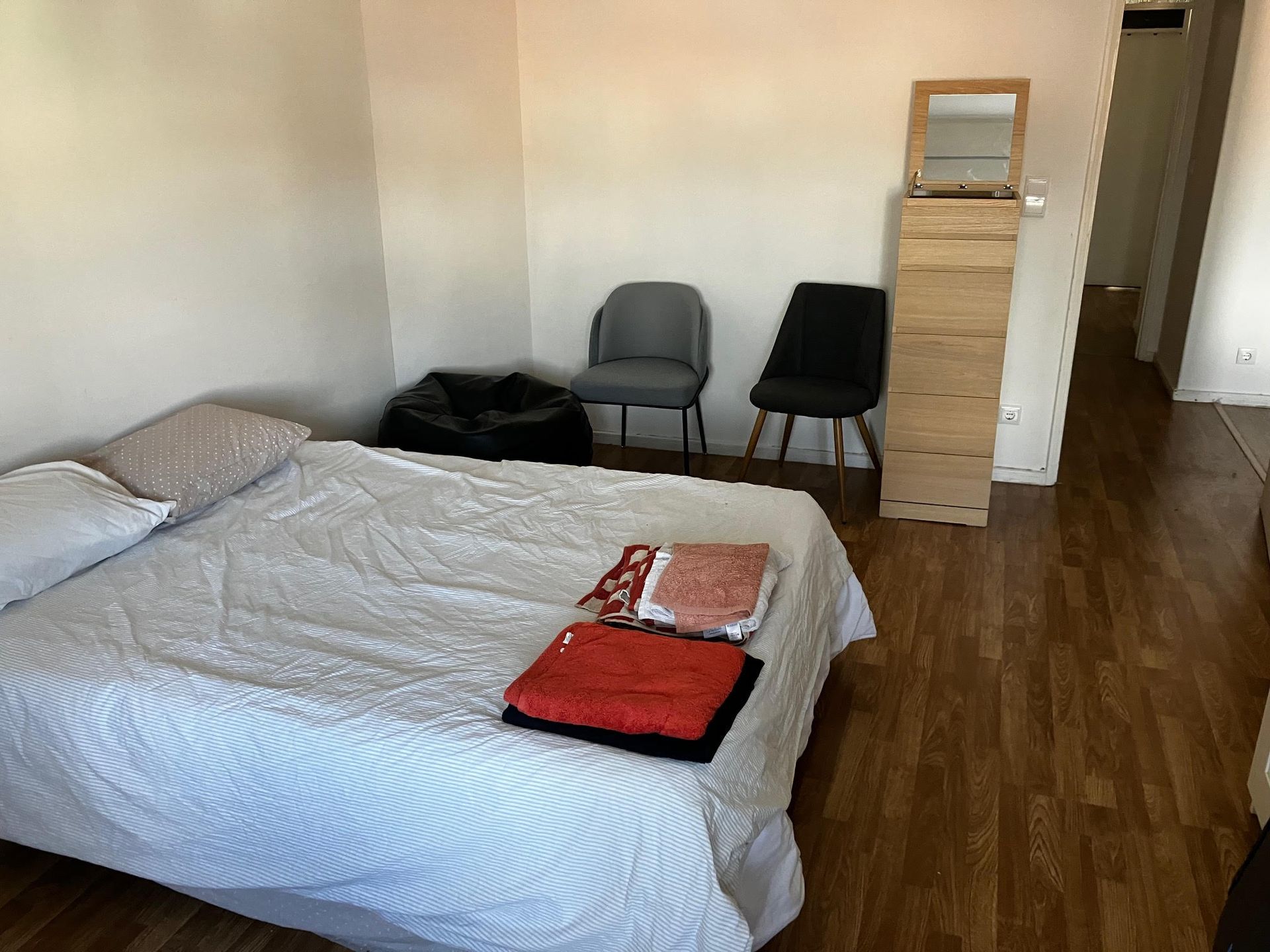 A bedroom with a bed and chairs and a mirror