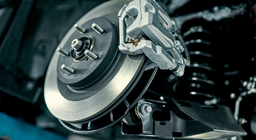 Close-up of a car's disc brake assembly, showing the rotor, caliper, and suspension components. | Allen's Automotive Service