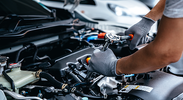 Mechanic working on car engine, using a wrench in a garage. | Allen's Automotive Service