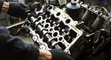 Hands with black gloves working on a car engine, shown disassembled with various parts. | Allen's Automotive Service
