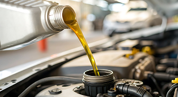 Pouring oil into a car engine from a silver bottle; garage setting. | Allen's Automotive Service