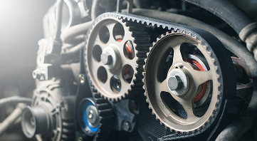 Close-up of engine parts: timing belt, pulleys, gears, and fasteners. | Allen's Automotive Service