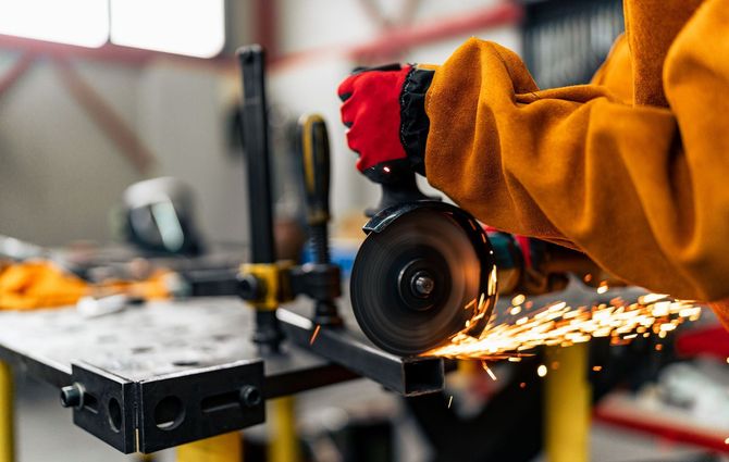 A person is using a grinder to cut a piece of metal.