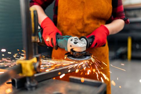 A person is grinding a piece of metal with a grinder.