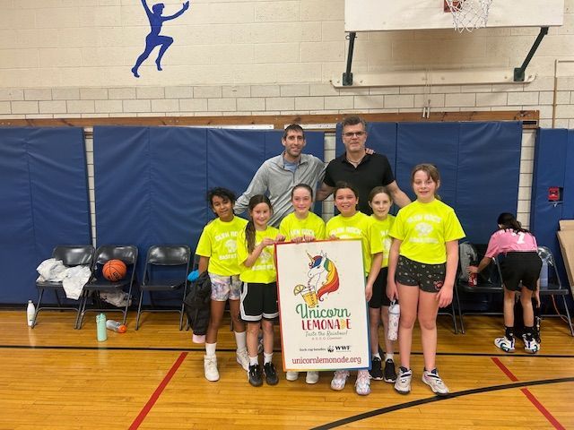 A group of young girls are posing for a picture on a basketball court.