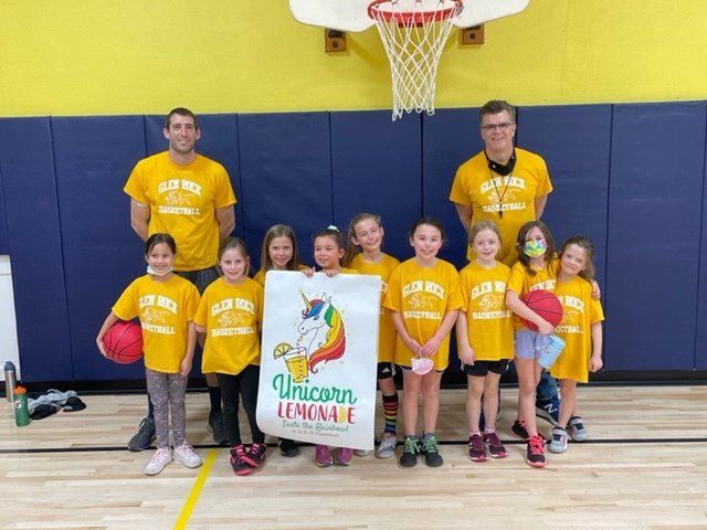 A group of children are posing for a picture on a basketball court.
