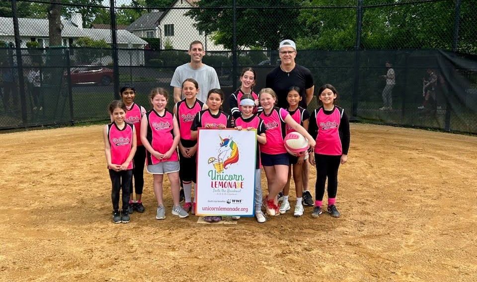 A group of young girls are posing for a picture on a baseball field.