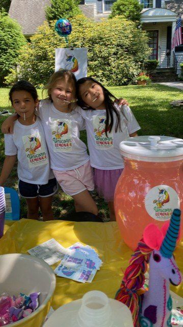 Three young girls are posing for a picture at a birthday party.