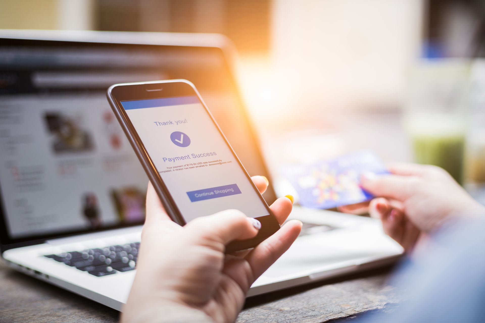 Person using a smartphone and credit card to make an online purchase on a laptop. Person using a smartphone and credit card to make an online purchase on a laptop.
