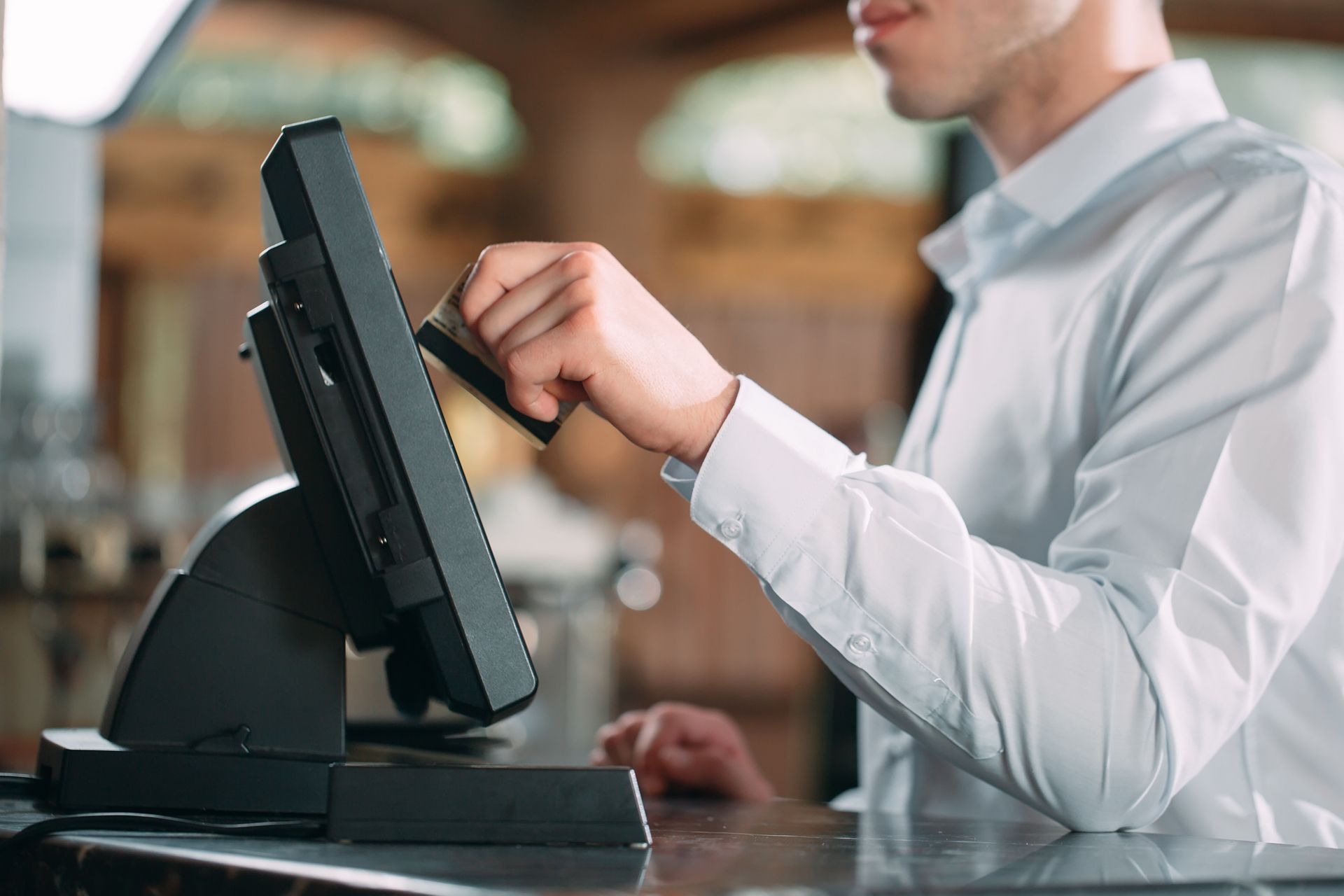 Person swiping a credit card on a point-of-sale system at a counter. Person swiping a credit card on a point-of-sale system at a counter.